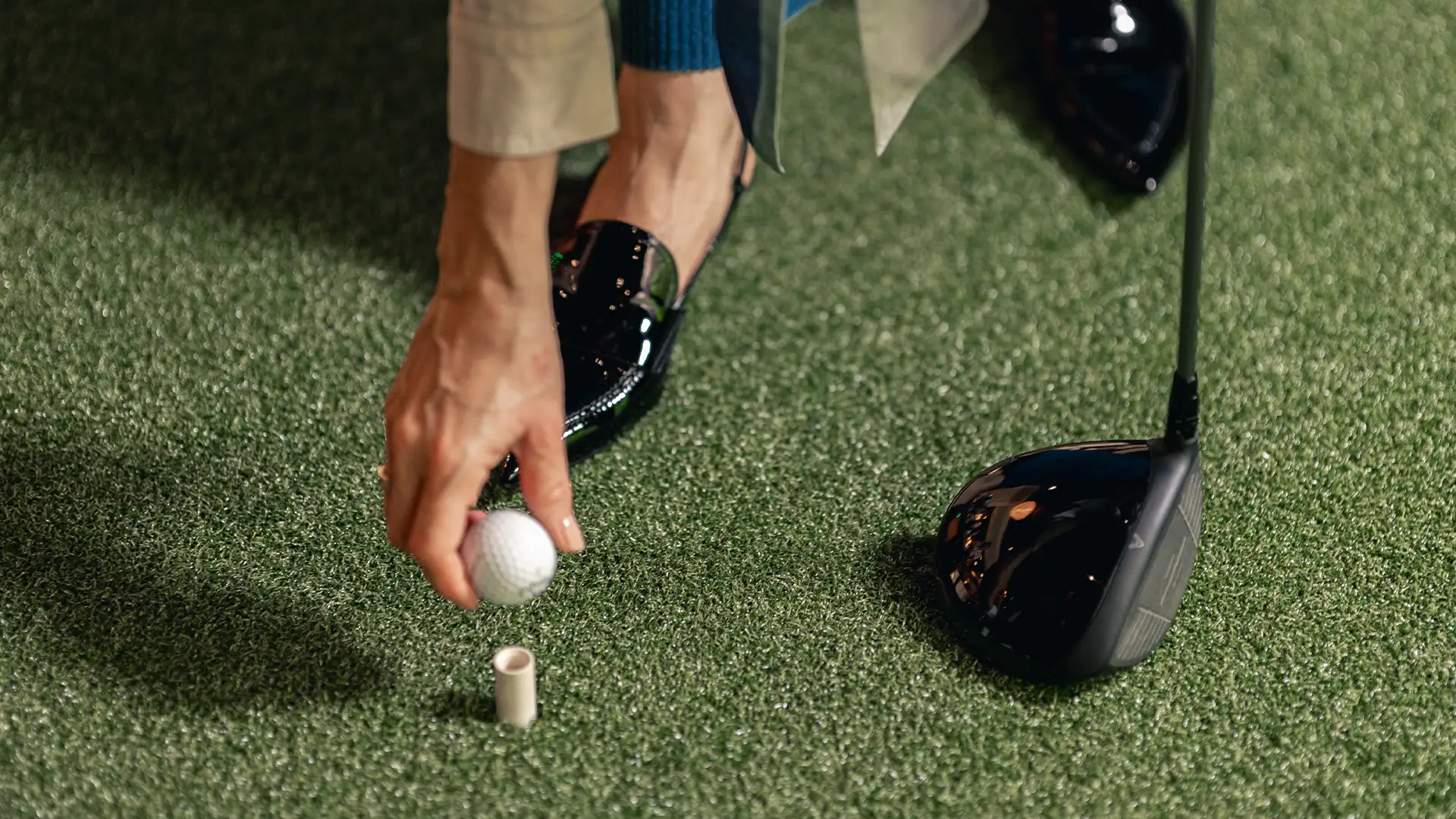 En person placerar en golfboll på en pegg inne på Jacy’z Fairway Fusion.