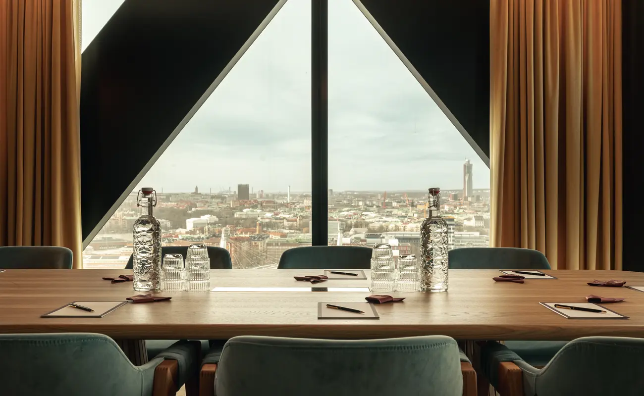 Ett elegant konferensrum på Jacy’z med panoramavy över Göteborg, uppdukat med anteckningsblock, pennor, glas och karaffer på ett stort träbord.