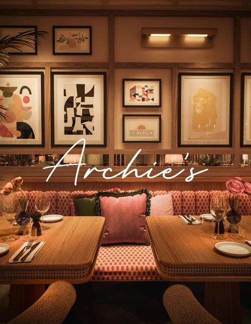 Mysig sittplats i Archie’s restaurang på Jacy’z i Göteborg. Soffa med fluffiga kuddar, dukat bord och konst på väggen.